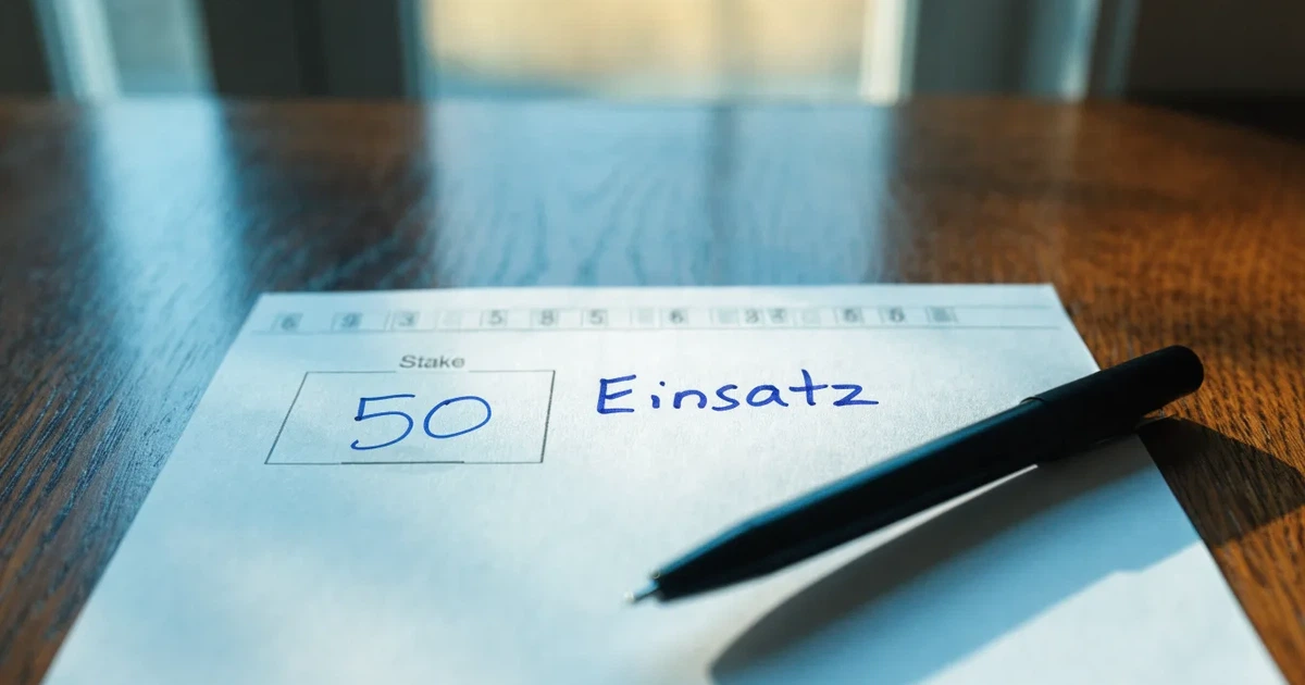 Ein leerer Papier-Wettschein liegt neben einem Kugelschreiber auf einem Tisch, ohne lesbaren Aufdruck.